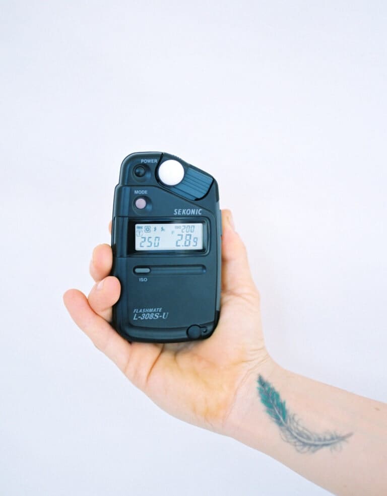 A hand holding a black light meter made by Sekonic.